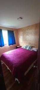 ein violettes Bett in einem Schlafzimmer mit einem Fenster in der Unterkunft Casa en la playa in Valdivia