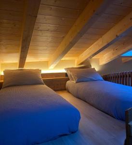 two beds in a room with wooden ceilings at Il fienile in Valfurva