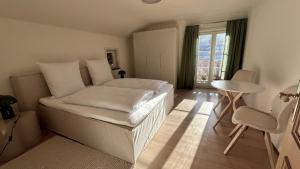 a bedroom with a bed and a table and a window at Die Talstation in Riezlern