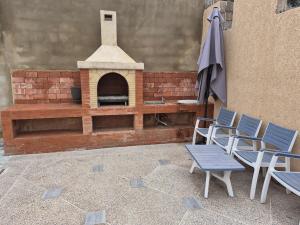 a patio with an outdoor oven and chairs and an umbrella at Villa avec Piscine Meknes in Meknès