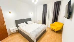 a bedroom with a bed and a yellow chair at Zarii Suites- Cotroceni in Bucharest