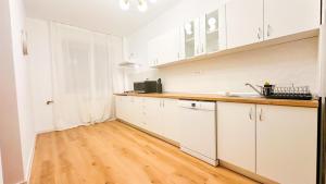 a kitchen with white cabinets and a wooden floor at Zarii Suites- Cotroceni in Bucharest +17 photos