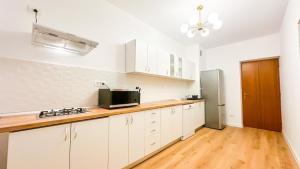 a kitchen with white cabinets and a refrigerator at Zarii Suites- Cotroceni in Bucharest