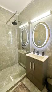 a bathroom with a sink and a shower with a mirror at Zarii Suites- Cotroceni in Bucharest