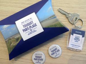 ein blauer Umschlag mit einem Schlüsselanhänger und einem Bild in der Unterkunft Résidence grand jardin attenant tennis, mini golf, sauna, pétanque in Stella-Plage