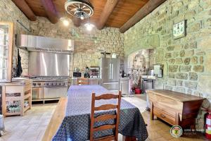 een grote keuken met een tafel en een stenen muur bij CHATEAU ROUSSET in St Apollinaire De Rias