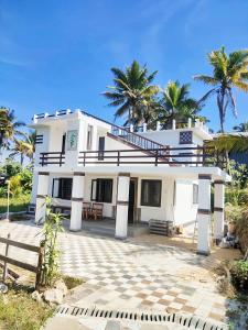 ein weißes Haus mit Palmen im Hintergrund in der Unterkunft Jessie Villas in Sultan Bathery