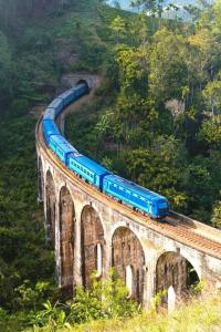 a blue train on a train track on a bridge at Auraya Ella in Ella