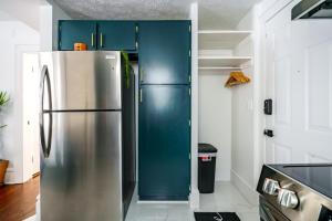 a stainless steel refrigerator in a kitchen with blue cabinets at Jungle House Luxury Stays - Columbus Downtown Short North in Columbus +52 photos