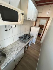 eine kleine Küche mit Herd und Mikrowelle in der Unterkunft Kitnet mobiliado no Caiçara, de fácil acesso ao centro e shopping in Belo Horizonte + 1 Foto