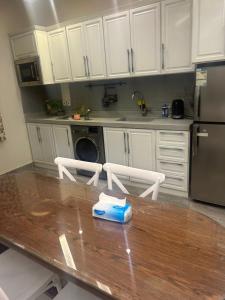 een keuken met een houten tafel en witte kasten bij شاليهات ايفا in Taif