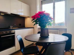 a kitchen table with a vase with red flowers on it at Charming Central Relais in Bergamo +17 photos