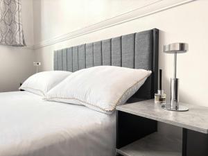 een slaapkamer met een wit bed met een grijs hoofdeinde bij York City Centre Flat with view - Best Location - Walk to Everything in York