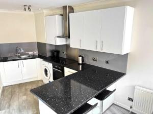 een keuken met witte kasten en een zwart aanrechtblad bij York City Centre Flat with view - Best Location - Walk to Everything in York