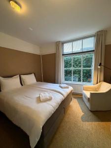 a bedroom with a large bed and a chair and a window at The Guesthouse in Gouda