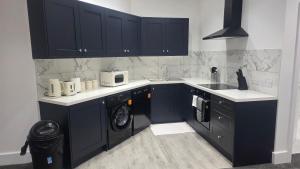 a kitchen with black cabinets and a washing machine at Royal House by Bourne Hall in Bournemouth