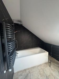 La salle de bains est pourvue d'une baignoire blanche et de carrelage noir. dans l'établissement Guben Wohnungen ruhig, à Guben