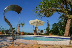 una piscina con un ombrellone, un tavolo e una fontana di Pousada da Encosta a Garopaba