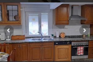a kitchen with wooden cabinets and a sink and a window at Casa da Tita in Peña de Folenche