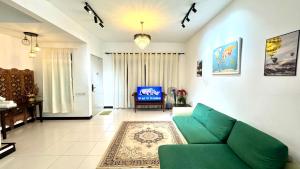 a living room with a green couch and a television at Home Vacays - B1SM1LLAH in Batu Arang