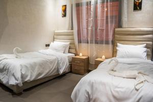 une chambre avec deux lits avec des draps blancs et des bougies dans l'établissement Sirajbeau miftah elkhair, à Béni Mellal