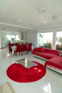 een woonkamer met een rode bank en een tafel bij Casa de Temporada in Monte Gordo