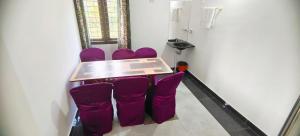 einen Tisch mit lila Stühlen in einem Zimmer in der Unterkunft Jessie Villas in Sultan Bathery + 3 Fotos