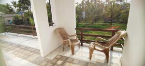 Zwei Stühle stehen auf einem Balkon und blicken auf einen Hof. in der Unterkunft Jessie Villas in Sultan Bathery