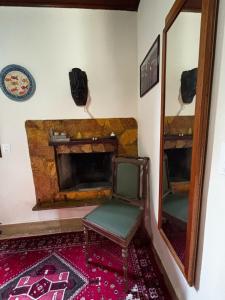 a room with a fireplace with a chair and a mirror at Cantinho da Serra do Cipó in Santana do Riacho
