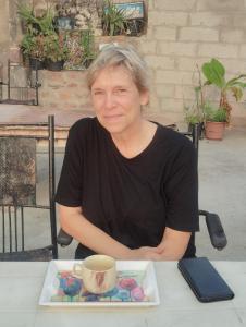 Eine Frau, die an einem Tisch mit einer Tasse Kaffee sitzt. in der Unterkunft UGS guest house in Jodhpur