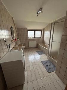 een badkamer met een bad, een wastafel en een douche bij Ferienwohnung Gaber in Reichshof 