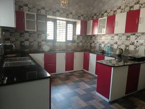 una cucina con armadi rossi e bianchi e un lavandino di Hridhayam Homestay varkala a Varkala Altre 19 foto