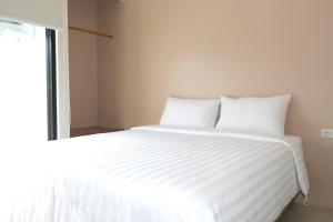 a white bed with white sheets and a window at Grownicle Living Syariah in Yogyakarta +19 photos