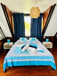 een bed met blauwe gordijnen en handdoeken erop bij Okilei House in Taputapuapea