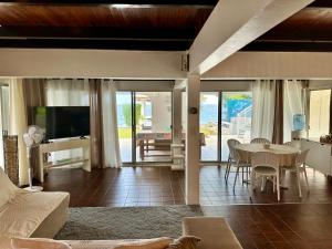een woonkamer met een tafel, stoelen en een televisie bij Okilei House in Taputapuapea