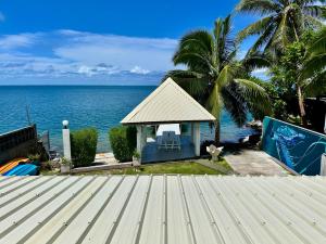 een prieel met een kat die naast de oceaan zit bij Okilei House in Taputapuapea
