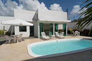 een huis met een zwembad en een tafel en stoelen bij Casa de Temporada in Monte Gordo