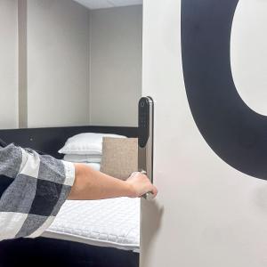 eine Person, die eine Tür zu einem Bett öffnet in der Unterkunft Nässjö Vandrarhem in Nässjö