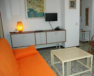 un soggiorno con divano arancione e TV di Villa Mary a Lignano Sabbiadoro