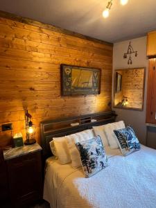 a bedroom with a bed with a wooden wall at The Mountain Escape - Luxury Apartment in Prato Nevoso
