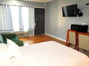 una camera da letto con un letto, un divano e una televisione di Americas Best Value Inn Suites & Studios Blytheville by Sonesta a Blytheville