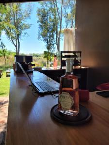 a bottle of alcohol sitting on a table next to a laptop at La Perdida Casa de Campo in San Antonio de Areco