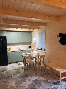 a kitchen and dining room with a table and chairs at W Sam Las Komfortowy domek na skraju lasu z gorącą balia in Orzyny