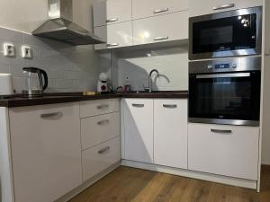 eine Küche mit weißen Schränken und einer Mikrowelle in der Unterkunft Relax & Luxury apartment in Veľká Lomnica