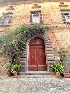 een bruine deur op een bakstenen gebouw met planten bij DIMORA MedioEvo in Orvieto
