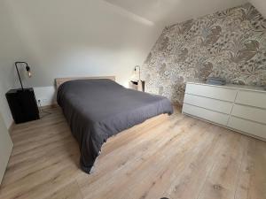 ein Schlafzimmer mit einem Bett, einer Kommode und einer Wand in der Unterkunft Gîtes du phénix in Pont-Aven