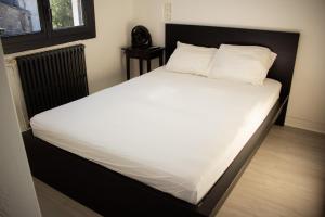 Elle comprend un grand lit avec des draps et des oreillers blancs. dans l'établissement Charmant studio 2 pièces entièrement équipé,, à Chenac-sur-Gironde