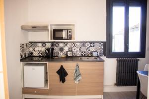 une cuisine avec un évier et un micro-ondes dans l'établissement Charmant studio 2 pièces entièrement équipé,, à Chenac-sur-Gironde