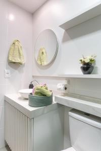 a white bathroom with a sink and a mirror at Season Smart Flat Ipojuca in Porto De Galinhas