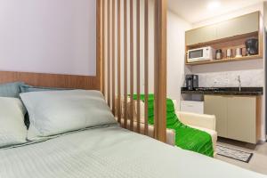 a bedroom with a bed and a kitchen with a microwave at Season Smart Flat Ipojuca in Porto De Galinhas
